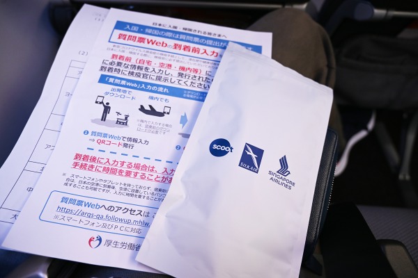シンガポール航空の復路機内で配られた「ケアキット」や日本政府からの入国用書類。ケアキットにはマスクと手指消毒剤、消毒ウェットティッシュ入り（往路では配布なし）。 ちなみに、往路で認められたジョギング用マスクが復路では認められず不織布製の着用を求められるなど混乱も。