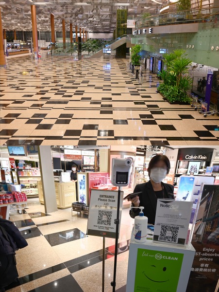 （上）チャンギ空港の出国審査場前ロビー。23時頃のせいか旅客は1人もいない。 （下）免税店はほとんど開いていない。入店する際はシンガポール国内と同様に体温とQRコードのスキャンが必要。トークンは返却済みなのでパスポートで処理をしてもらうことに。