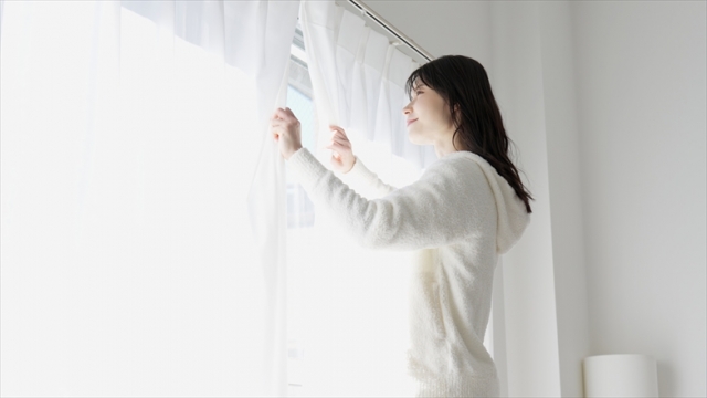 カーテンを開ける女性